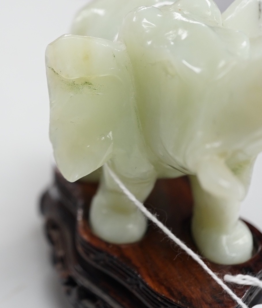 A Chinese bowenite jade elephant on hard wood stand, 11cm tall